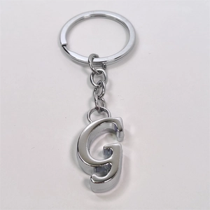 Detailed view of a silver metal keychain featuring a polished letter G charm on a white base
