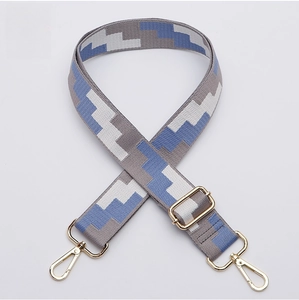 Close-up of thick wide shoulder strap with blue gray geometric pixel pattern and gold buckle