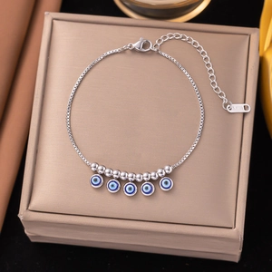 Silver stainless steel bracelet with blue evil eye charms on a golden jewelry box