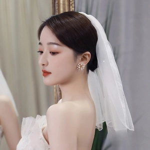Detail of short white bridal veil with shimmering edges and elegant pearl flower earrings