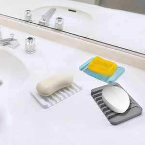 Close-up of three silicone soap dishes in white, blue, and gray on a bathroom sink