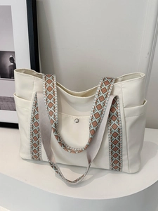 Dettaglio della borsa tote bianco sporco con tracolla etnica larga e tasca con bottone