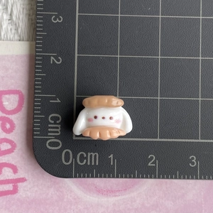 Miniature resin rabbit bead for DIY crafts measured on a centimeter grid mat