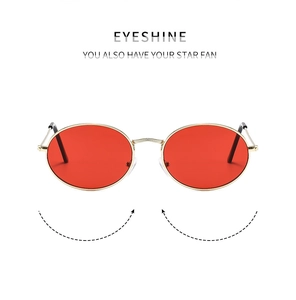 Detail of retro oval sunglasses with gold metal frame and vibrant red lenses