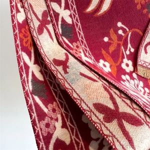 Macro detail of wine red scarf featuring floral patterns and soft woven fabric texture