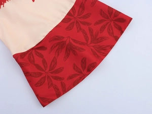 Detailed close-up of beige and red leaf print fabric on the Hawaiian dress hem