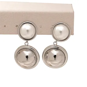 Détail de boucles d'oreilles argentées avec sphère supérieure mate et sphère inférieure miroir
