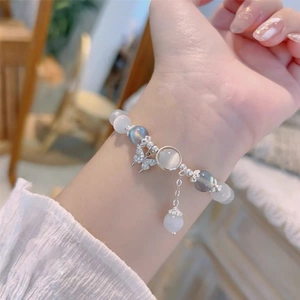 Gros plan d'un bracelet en perles avec breloque papillon en argent et pierres de lune