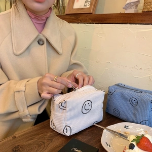 Detail of corduroy makeup bag with smiley pattern featuring blue and white textures