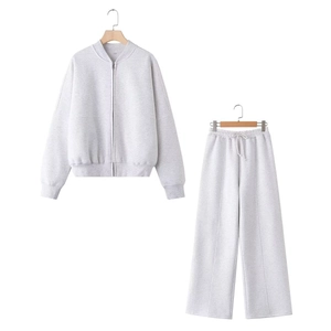 Detail of light grey zip-up bomber jacket and wide-leg joggers set on a wooden hanger