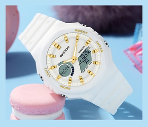 Close-up of a white and gold dual display digital watch on a pink macaron