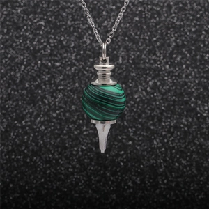 Macro shot of silver hollow bead pendant with green malachite ball on dark glitter background