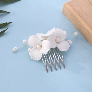 Detail of white ceramic magnolia hair comb with pearls and silver metal teeth on blue background