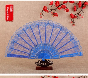 Close-up of elegant blue lace folding fan with floral patterns on a wooden stand
