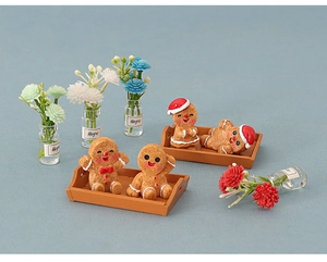 Miniature gingerbread man figurines on small wooden trays with floral decorative bottles