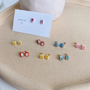 Macro view of rectangular enamel stud earrings with crystal center on a tray