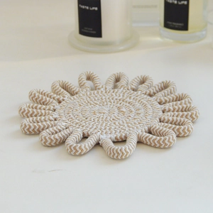 Detail of flower-shaped woven cotton placemat with beige and white herringbone pattern