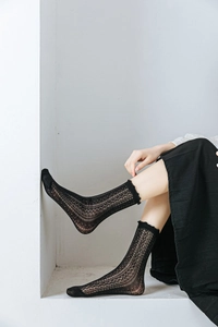 Detail of black lace crew socks with ruffle mesh cuffs and intricate floral weave pattern