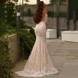 Elegant white lace mermaid wedding dress with open back and long sleeves in outdoor setting