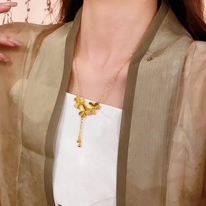 Close-up of gold-plated four-leaf clover tassel necklace worn by a female model