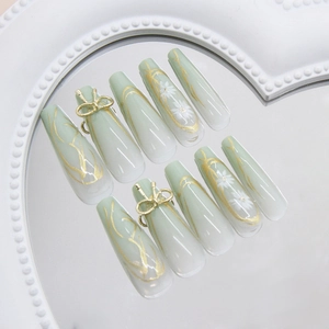 Green and white gradient press-on nails with 3D gold bows and daisy floral accents