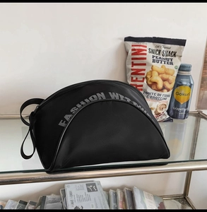 Détail d'un sac bandoulière en nylon noir avec un grand slogan FASHION imprimé en gris