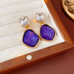 Gros plan de boucles d'oreilles vintage dorées avec pierres violettes sur un plateau