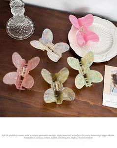 Detail view of colorful marble acetate butterfly hair claws on a wooden table setup