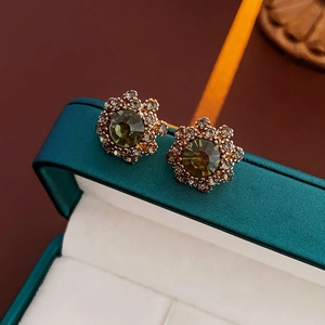 Close-up of vintage flower earrings with olive green stones and champagne crystals