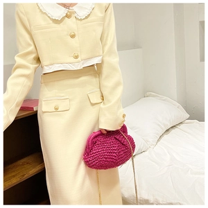 Close-up of model holding a rose red straw clutch bag with a textured woven design