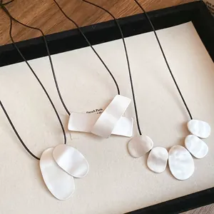 Minimalist geometric metal pendants on black leather cords in three abstract styles