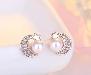 Macro detail of rose gold moon and star stud earrings with zircon and pearls