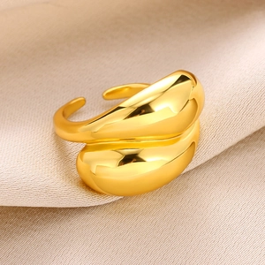 Close-up of golden double-layered teardrop ring on soft beige satin fabric background