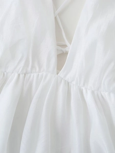 Detailed view of white backless satin dress showing criss-cross lace-up and silk texture