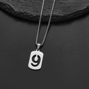 Macro view of silver stainless steel number 9 pendant necklace on a black stone surface