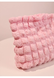 Primer plano de neceser rosa con textura de burbujas 3D y tela suave elástica