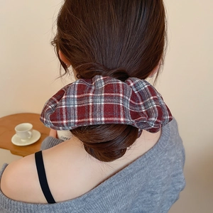 Detailed view of large classic British plaid scrunchie styled on model's hair ponytail