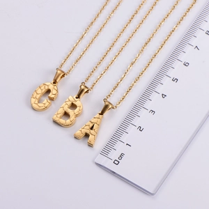 Macro view of 18K gold plated initial pendants with unique stone texture and ruler scale