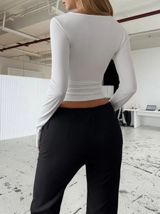 Back view of a white Y2K lace long sleeve top with black pants on a fashion model