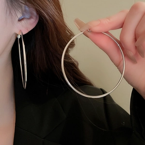 Close-up of oversized silver hoop earrings showing smooth metallic finish and large fit