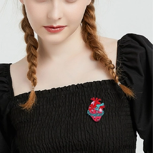 Gothic anatomical heart brooch with blue and red enamel vines worn on black clothing