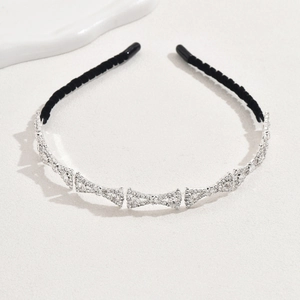 Detailed view of silver crystal bow headband with black velvet tips on white surface