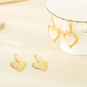 Detail view of gold heart earrings with cat eye stone inlay and hammered metal texture