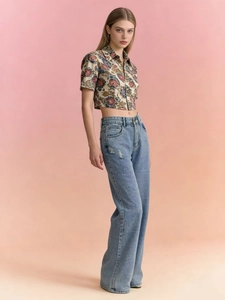Détail d'un jean taille haute à jambes larges porté avec un haut court à fleurs rétro