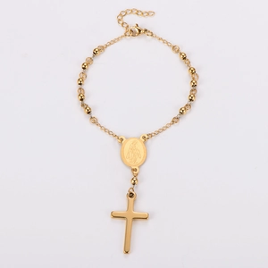 Detail of gold beaded rosary bracelet featuring a Virgin Mary medal and polished cross pendant