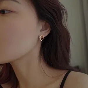 Close-up of minimalist gold geometric diamond earrings worn by a model in soft lighting