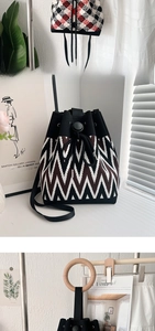 Detail of knit bucket bag with drawstring closure and circular wooden handle