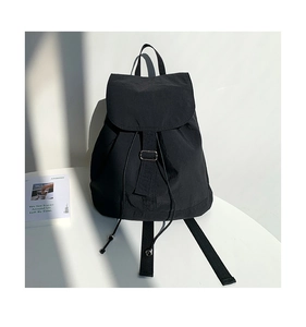Dettaglio dello zaino in nylon nero minimalista con chiusura a cordoncino e fibbia