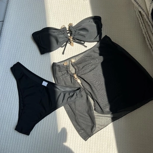 Détail du bikini 3 pièces noir avec jupe en résille et boucles en forme de cœur dorées