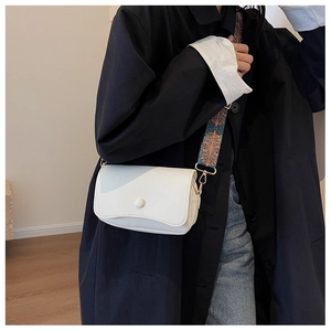 Close-up of white lychee leather crossbody bag with colorful ethnic style wide strap